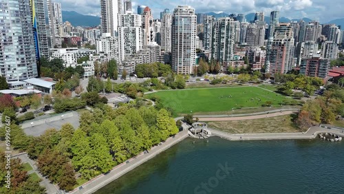 Drone shot of a park by downtown Vancouver buildings. David Lam park where kids are playing and seawall with people walking and running. photo