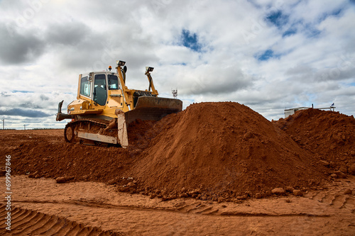 A yellow tractor levels the site with sand