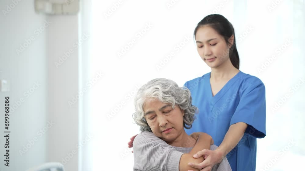 Physiotherapist doing physical therapy to an elderly Asian woman examining the treatment of a female patient's injured arm to rehabilitate the painful arm with a female doctor Health care concept Physiotherapist doing physical therapy to an elderly Asian woman examining the treatment of a female patient's injured arm to rehabilitate the painful arm with a female doctor Health care concept