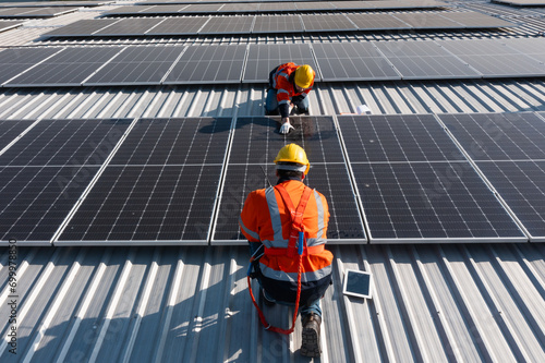 Two caucasian engineering technician is a professional trained in skills and techniques installing solar photovoltaic panels system on industrial factory roof, Engineering concepts to good environment photo