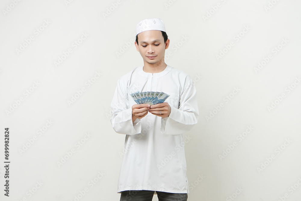 happy muslim man holding money rupiah banknotes. People religious Islam lifestyle concept. celebration Ramadan and ied Mubarak. on isolated background. happy muslim man holding money rupiah banknotes. People religious Islam lifestyle concept. celebration Ramadan and ied Mubarak. on isolated background.