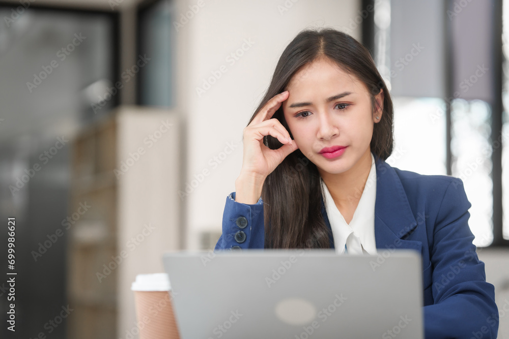stressed young businesswoman with a credit card in hand, looking worried in front of her laptop. stressed young businesswoman with a credit card in hand, looking worried in front of her laptop.