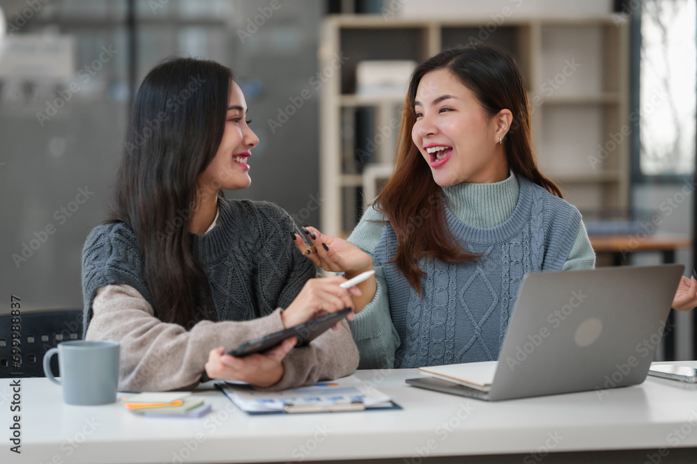 Two Asian individuals, possibly friends, studying together with a tablet and a laptop on the table. Two Asian individuals, possibly friends, studying together with a tablet and a laptop on the table.