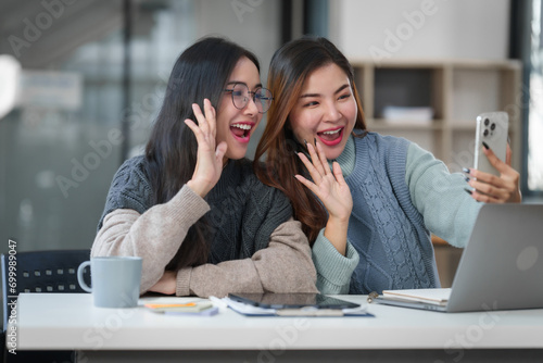 Two Asian individuals, possibly friends, studying together with a tablet and a laptop on the table.