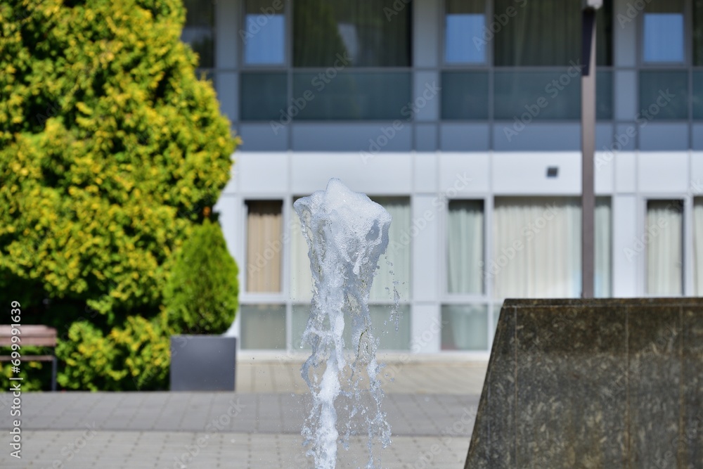 A view of water splashing from a fountain in a city park