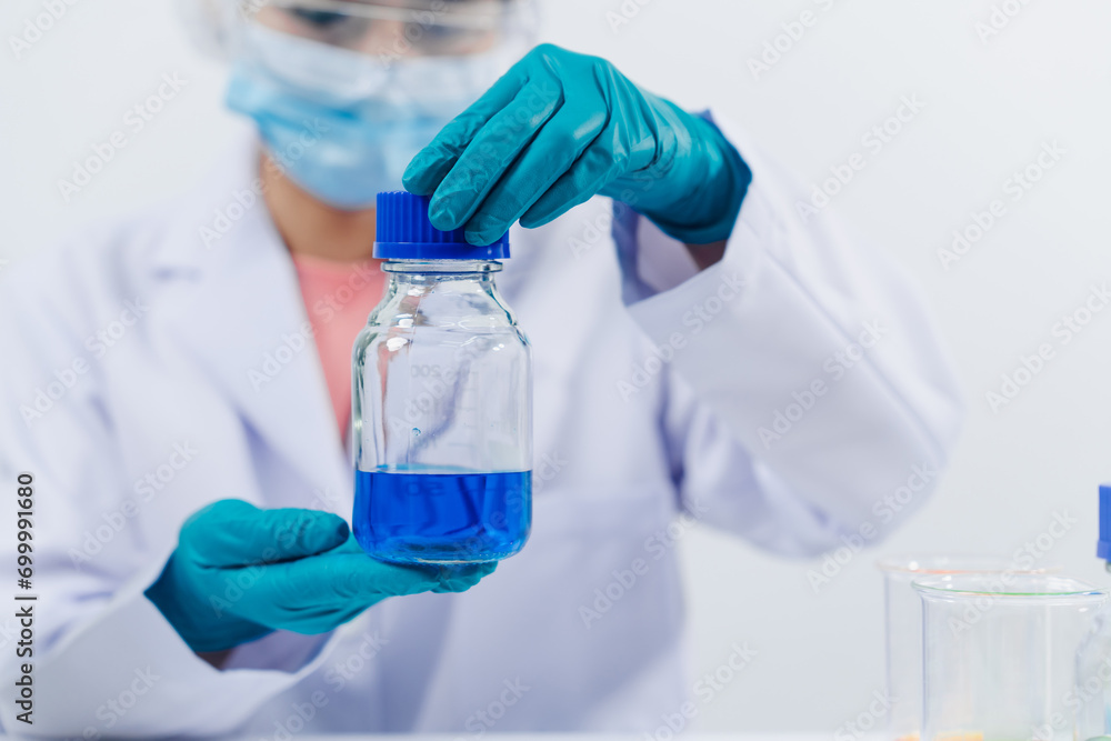A scientist examines samples with a microscope in a laboratory with test tubes filled with colorful liquids in the background. A scientist examines samples with a microscope in a laboratory with test tubes filled with colorful liquids in the background.