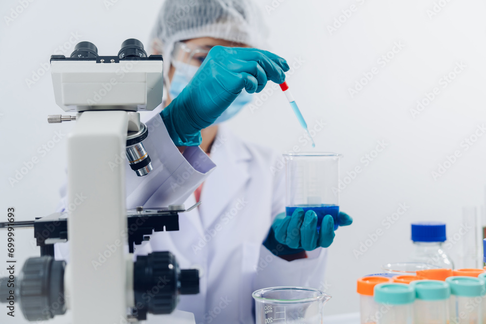 A scientist examines samples with a microscope in a laboratory with test tubes filled with colorful liquids in the background. A scientist examines samples with a microscope in a laboratory with test tubes filled with colorful liquids in the background.
