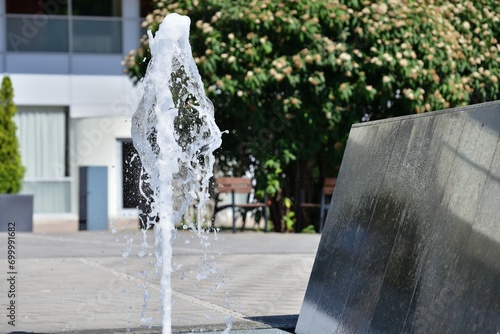 Obraz na płótnie The urban white water fountain sprays up a geyser of water in the summer w salonie
