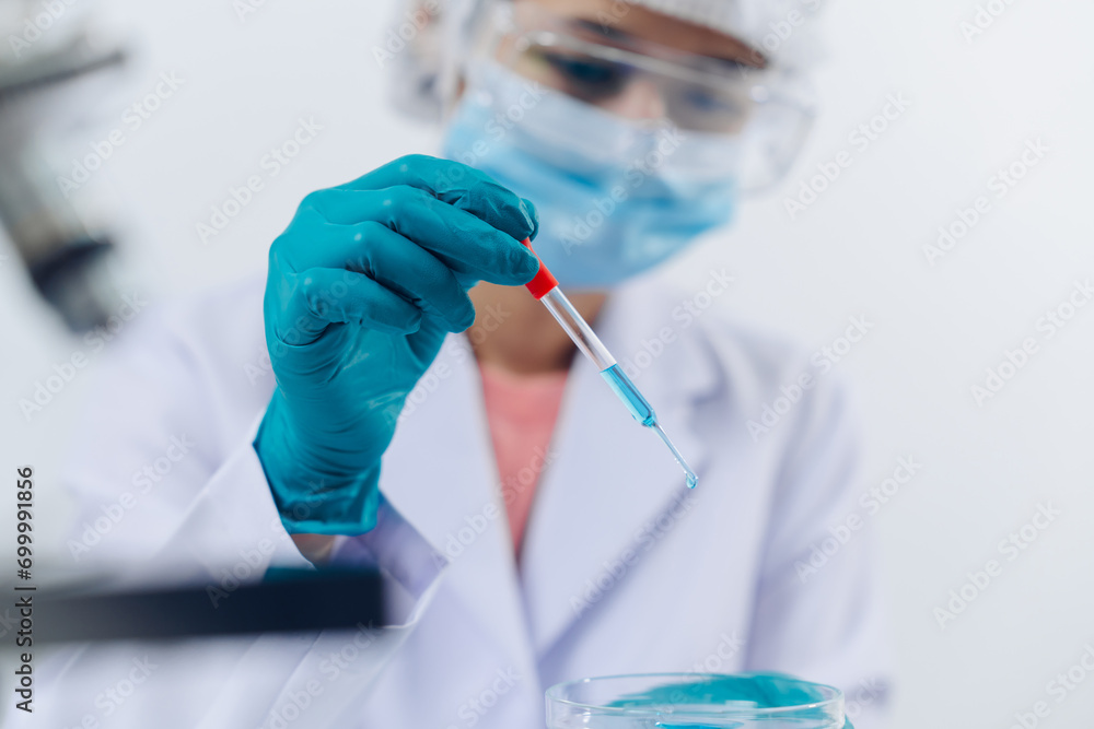 A scientist examines samples with a microscope in a laboratory with test tubes filled with colorful liquids in the background. A scientist examines samples with a microscope in a laboratory with test tubes filled with colorful liquids in the background.