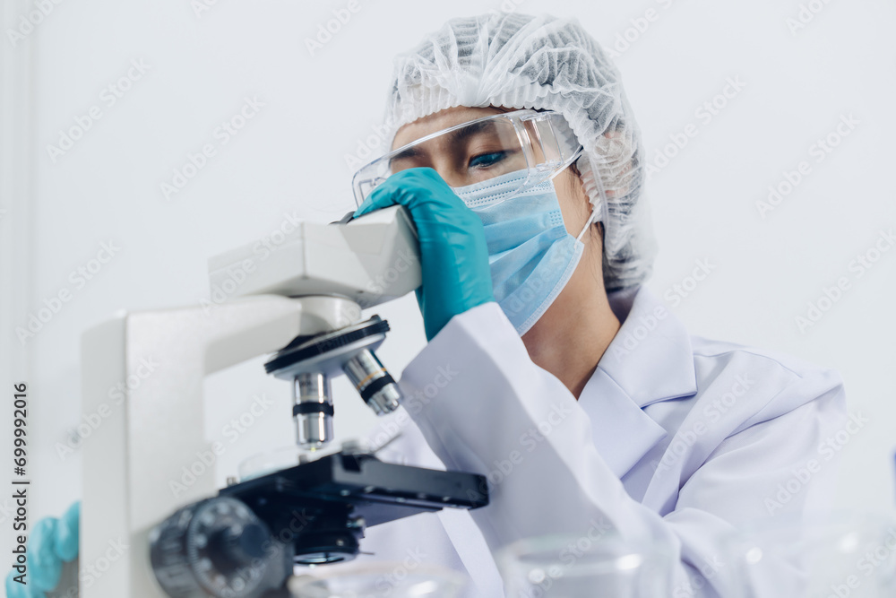 A scientist examines samples with a microscope in a laboratory with test tubes filled with colorful liquids in the background. A scientist examines samples with a microscope in a laboratory with test tubes filled with colorful liquids in the background.