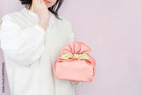 贈り物に悩む女性のイメージ　ピンク背景 photo