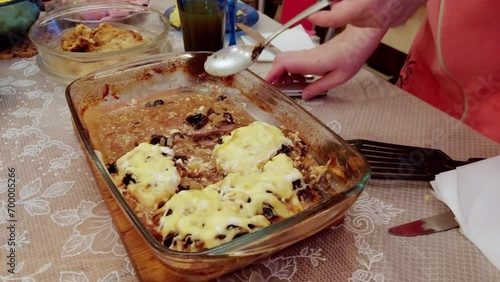 The girl puts fatty meat with mayonnaise and cheese on a plate with a spoon. Unhealthy foods with cholesterol, close-up photo