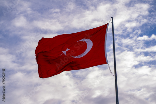 Waving Turkish flag and clouds in the background.