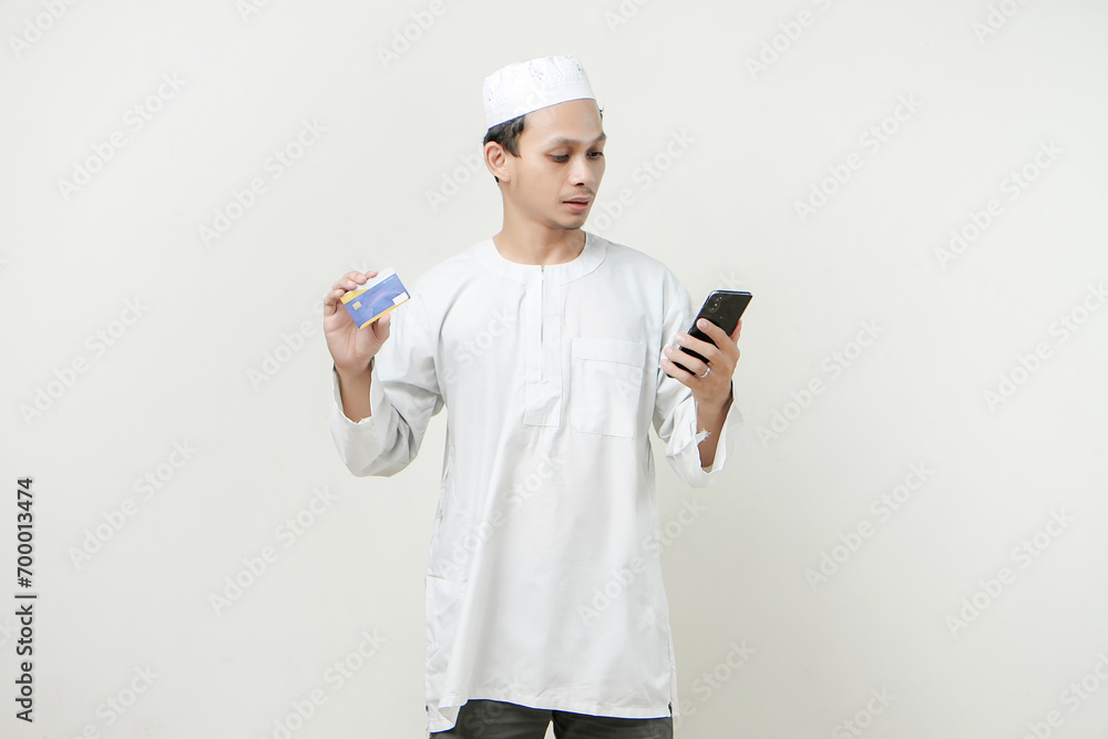 handsome asian man holding credit card and mobile phone on isolated background handsome asian man holding credit card and mobile phone on isolated background