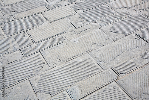 Old and damaged italian paving made with chiseled grey sandstone blocks in a pedestrian zone - The surface part is being damaged due to the freeze and thaw cycles that break the stone photo