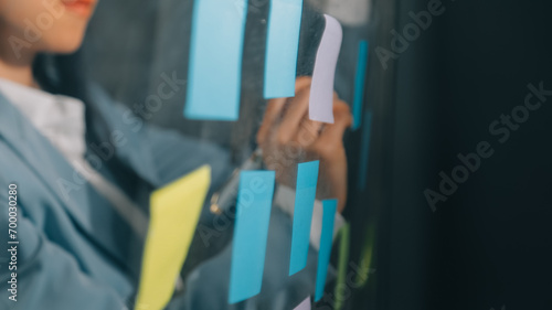 Young creative team professional using post it notes in glass wall to writing strategy business plan to development grow to success.