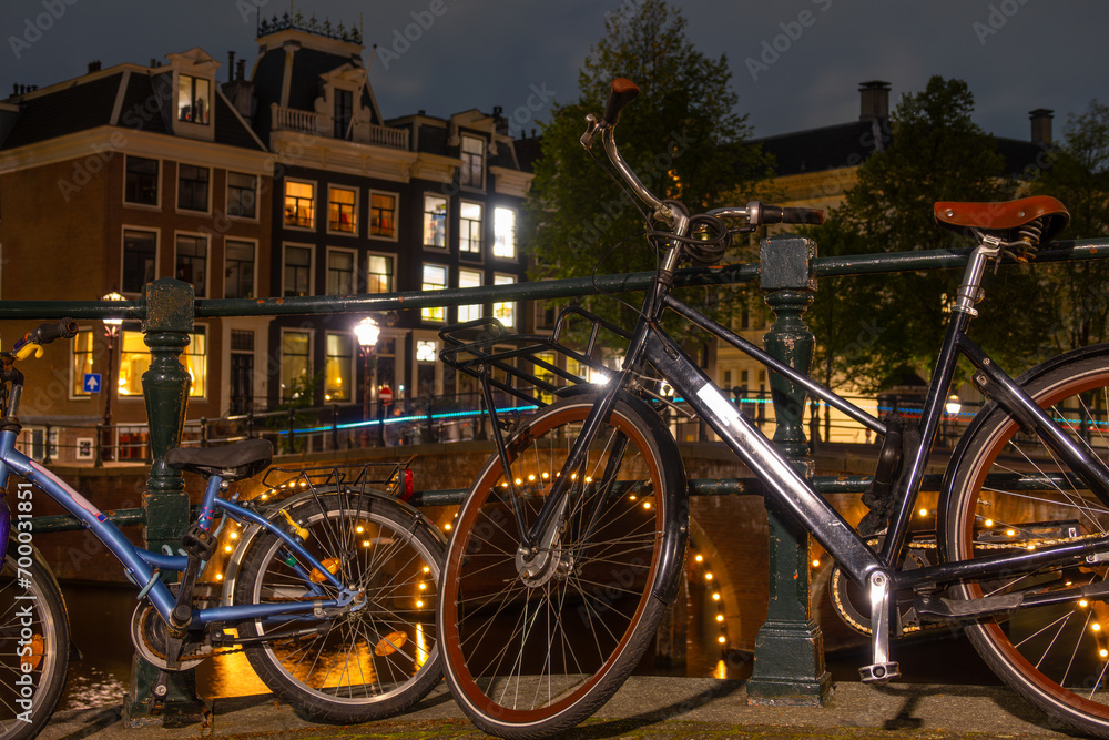 Adult and Children's Bikes on the Canal Embankment in Amsterdam at Night