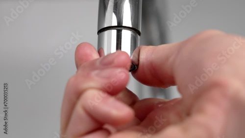 Repairing a kitchen faucet with unscrewing a damaged filter aerator with leaking water close up photo