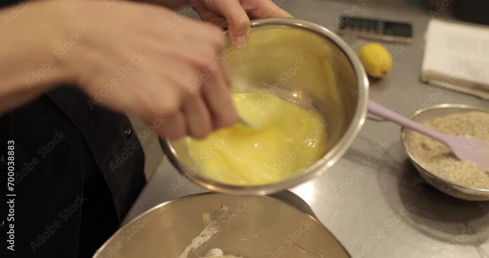 A professional pastry chef woman mixes eggs and adds them to a large bowl to prepare the dough A professional pastry chef woman mixes eggs and adds them to a large bowl to prepare the dough