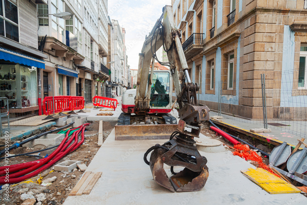 Naklejka premium Repairing a road and laying communications using an excavator on the streets of the Italian city of Taranto.