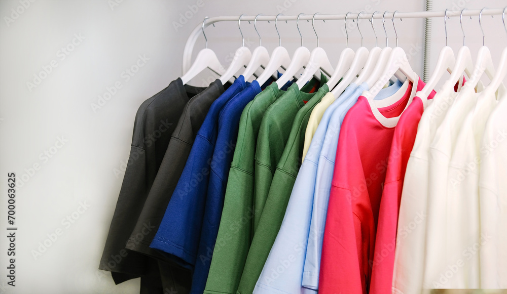 Shopping Concept. Clothing Rail With Bright Trendy Clothes Hanging On Hangers Over White Studio Background In Empty Room. Fashion Trends And Style Shopping Concept. Clothing Rail With Bright Trendy Clothes Hanging On Hangers Over White Studio Background In Empty Room. Fashion Trends And Style