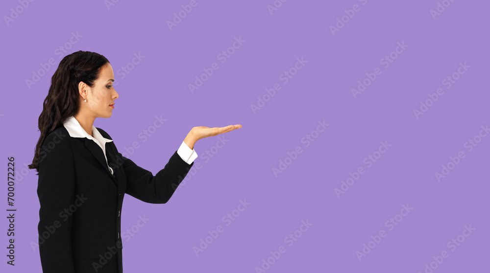 Profile side of beautiful businesswoman showing something or copy spase for product. Brunette woman looking at her hand in business cstudio concept, isolated violet purple background. Profile side of beautiful businesswoman showing something or copy spase for product. Brunette woman looking at her hand in business cstudio concept, isolated violet purple background.