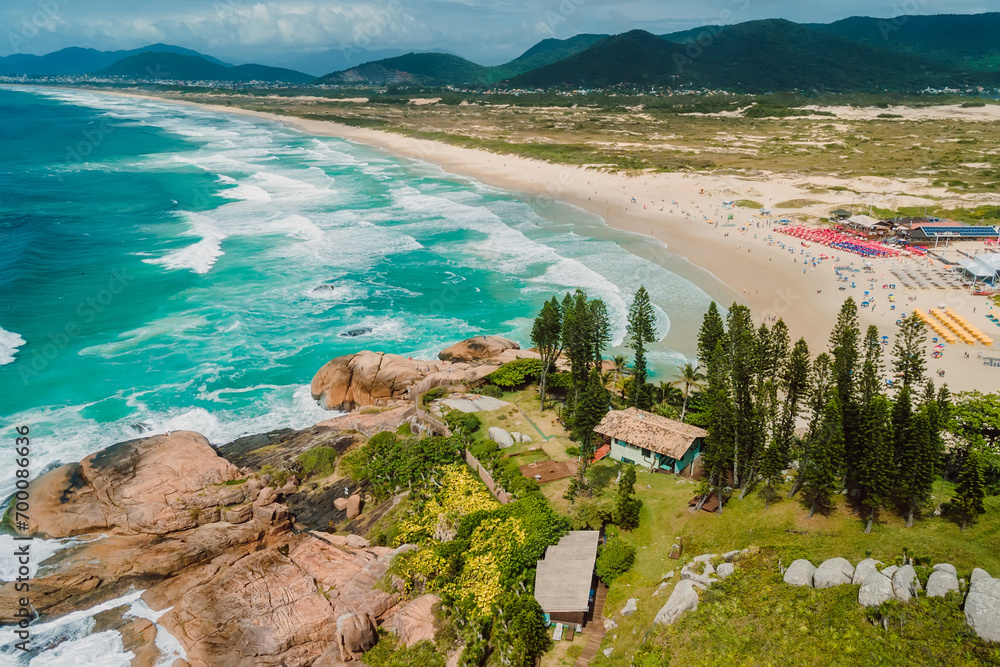 Popular holiday beach with trees and ocean with waves in Brazil. Aerial view of coastline