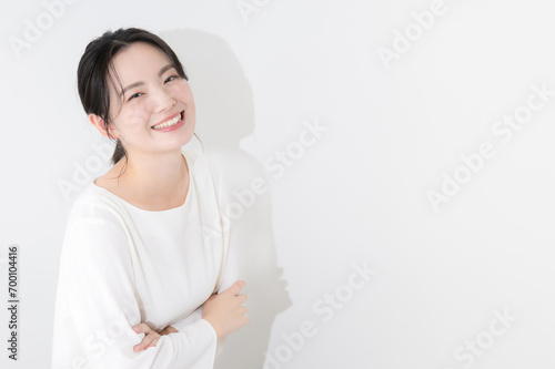 白い壁の前で腕を組み笑顔の若い女性のカメラ目線,上半身 photo