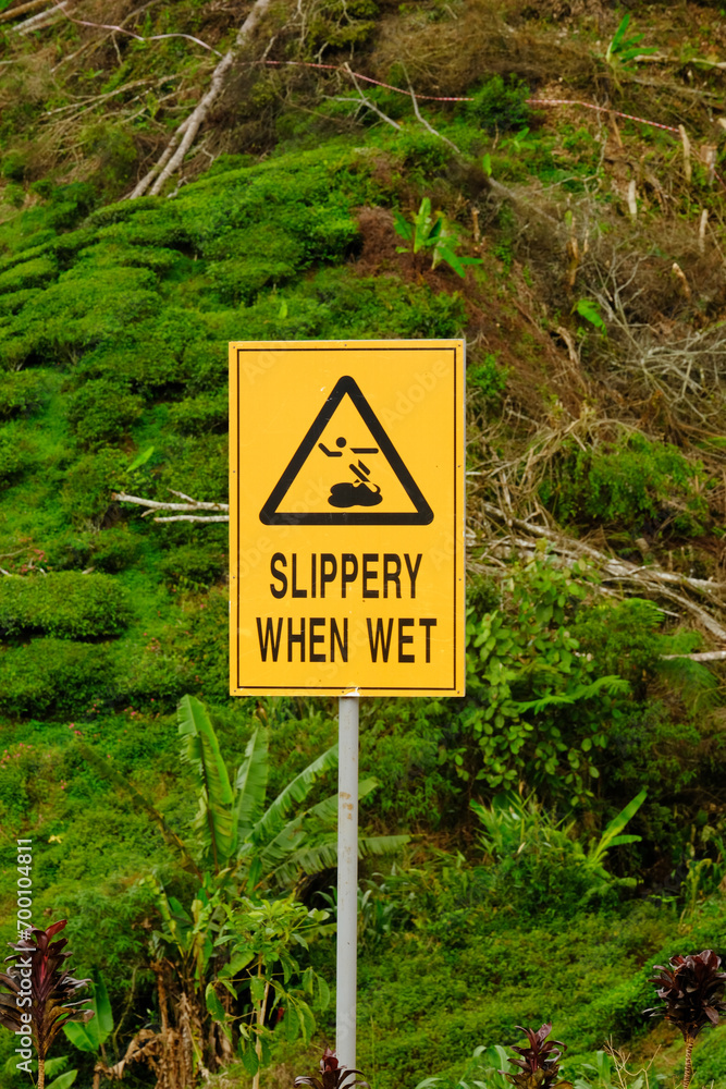 Selective focus picture of slippery when wet sign at tea plantation.