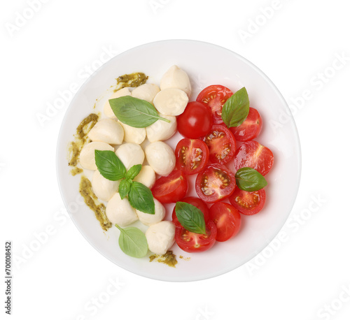 Plate of tasty Caprese salad with mozzarella, tomatoes, basil and pesto sauce isolated on white, top view