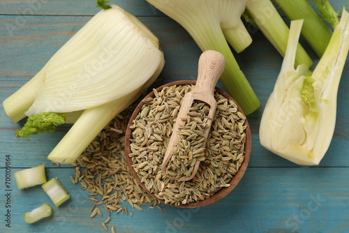 Fennel seeds in bowl, fresh vegetables and scoop on light blue wooden table, flat lay