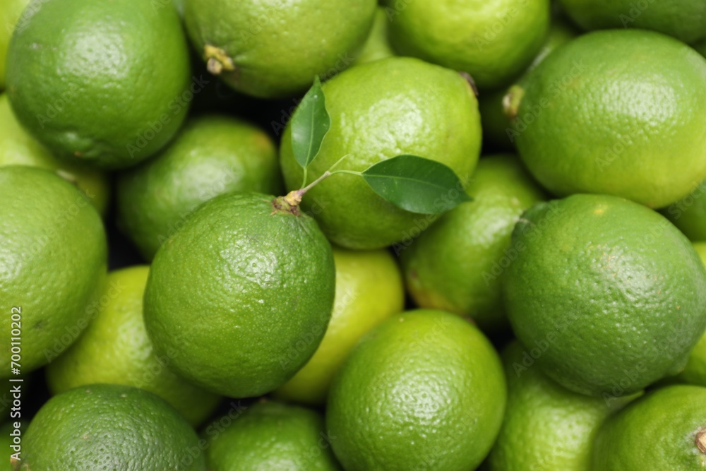 Many fresh limes with green leaves as background, top view Many fresh limes with green leaves as background, top view