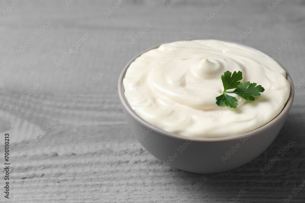 Tasty mayonnaise and parsley in bowl on gray wooden table, closeup. Space for text Tasty mayonnaise and parsley in bowl on gray wooden table, closeup. Space for text