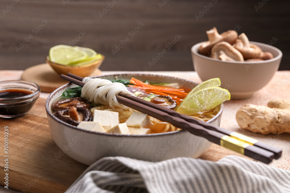 Fototapeta premium Bowl of vegetarian ramen and chopsticks on table, closeup