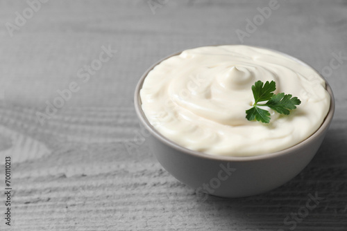 Tasty mayonnaise and parsley in bowl on gray wooden table, closeup. Space for text