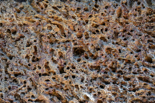 Close up of structured old holey porous stone wall surface for background pattern