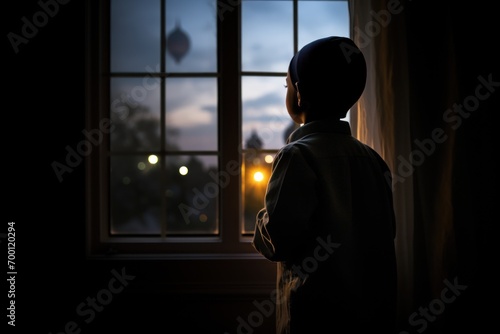 Muslim boy in taqiyah gazing at moon through window