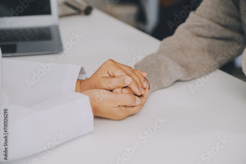 Doctor and patient sitting near each other at the table in clinic office. The focus is on female physician s hands reassuring woman  only hands  close up. Medicine concept