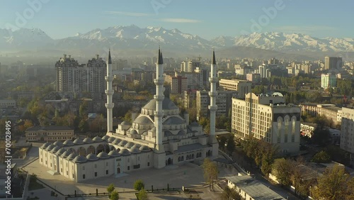 The Central mosque named after Imam Al Sarakhsi against the background of the snow-capped mountains of Kyrgyzstan. A circular flyby. The main attraction of Bishkek. photo