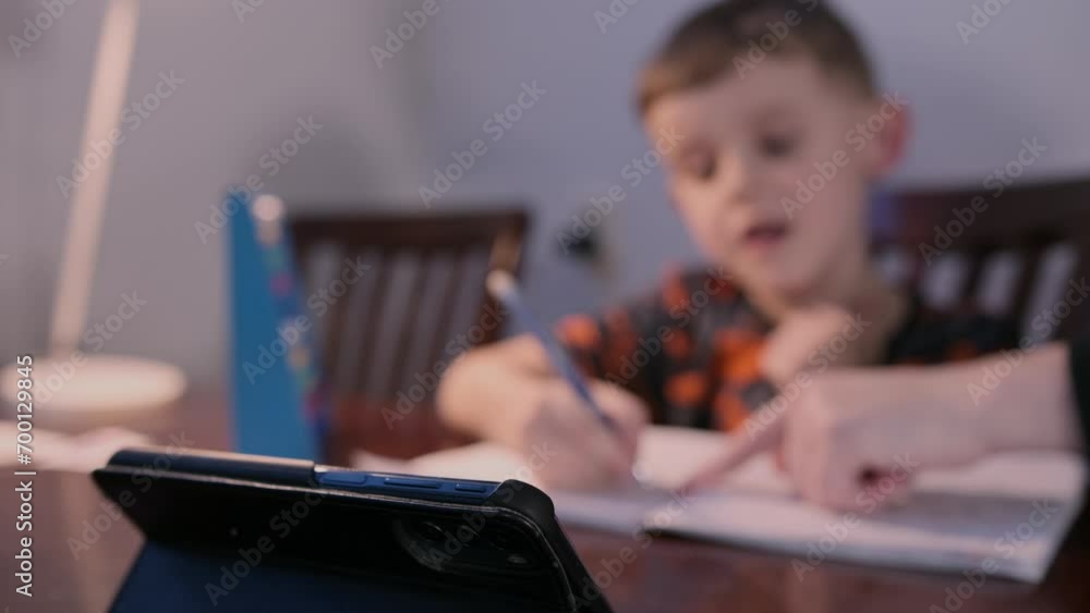 A preschool boy child studying lesson writing with pen. Serious kid primary class student write exercise homework home learning education A preschool boy child studying lesson writing with pen. Serious kid primary class student write exercise homework home learning education