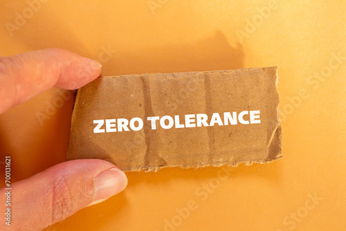 Zero tolerance lettering on ripped cardboard paper with orange background. Conceptual photo. Top view, copy space.