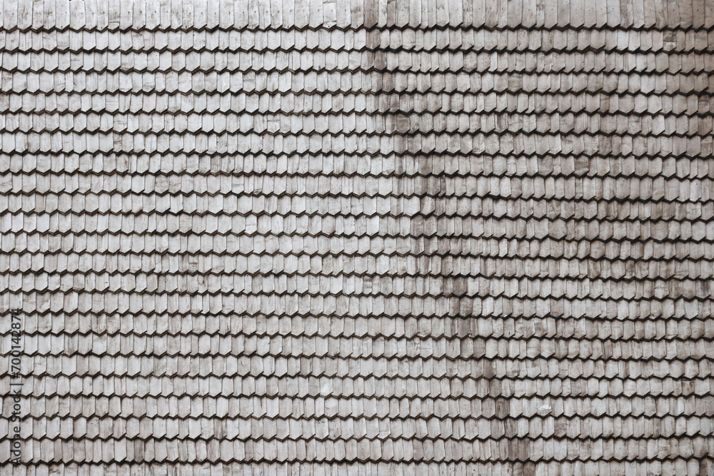 Gray wooden roof tiles background texture. A close up of old gray roof covered with wooden tiles or shingles Gray wooden roof tiles background texture. A close up of old gray roof covered with wooden tiles or shingles
