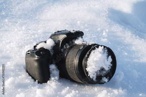 professional digital slr photo camera lies in a snowdrift in the snow in winter photo