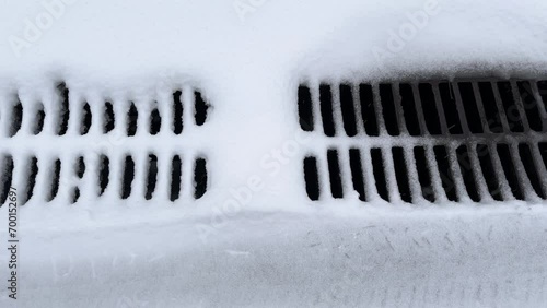 Snowy cast iron grid of storm drain during a snowfall photo