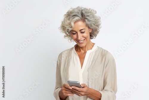 A smart and attractive senior woman using her phone, texting, and making calls in a studio setting.