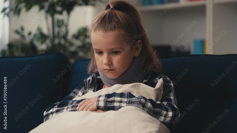 Upset little girl wearing cervical neck collar sitting on sofa at home, accident Upset little girl wearing cervical neck collar sitting on sofa at home, accident