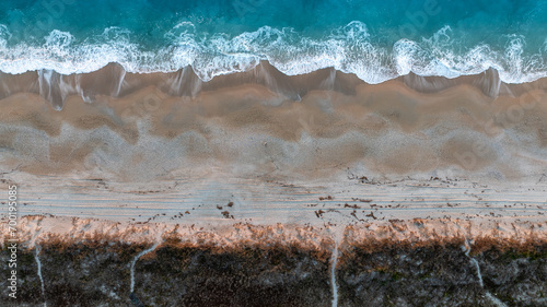 Top-down view of a beach with waves crashing onto the sand, demarcating the boundary between sea and shore photo