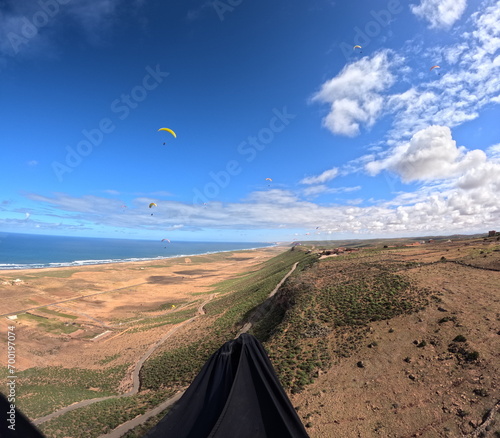 beauty of paragliding flying over scenic seaside landscape,sand dunes and mountain terrain,aerial apnorama landscape view,paragliding pilot with his paraglider wing,aerial extreme sports,action camera photo