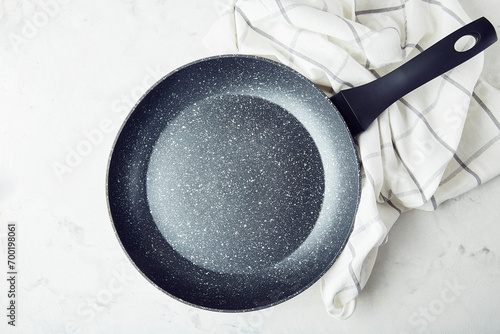 Black non-stick stainless steel frying pan on a marble background. Template. photo