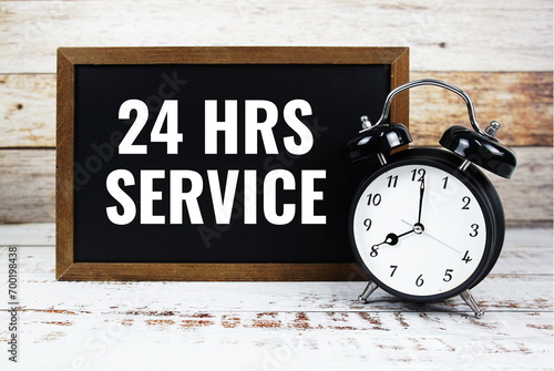 24 HRS Service text message with alarm clock on wooden background